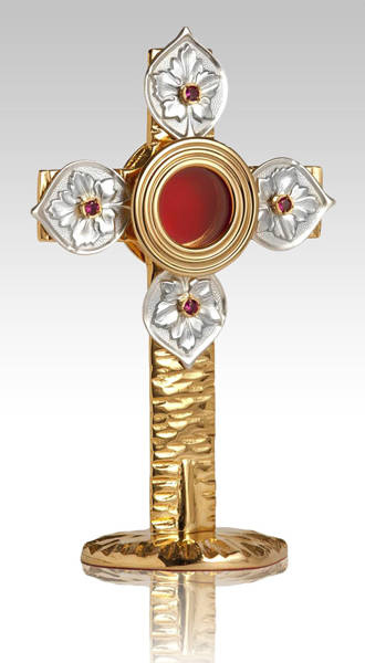 Relikwiarz mosiężny złocony w kształcie krzyża zdobiony srebrzonymi listkami, na jedną relikwię o wysokości 22 cm